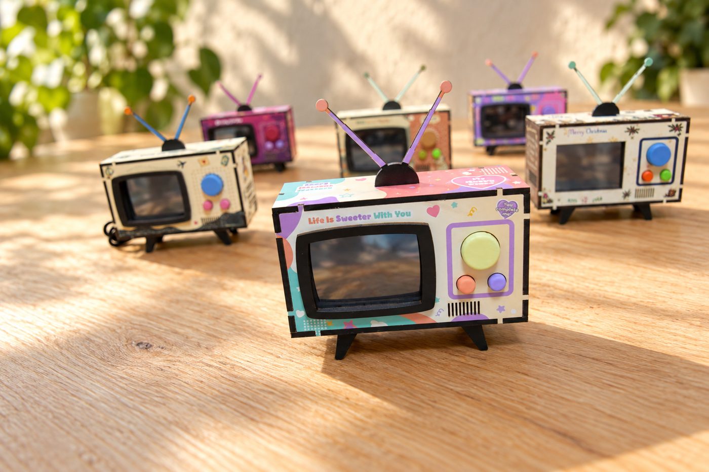 Several Mini TVs in different designs lined up on a wooden table